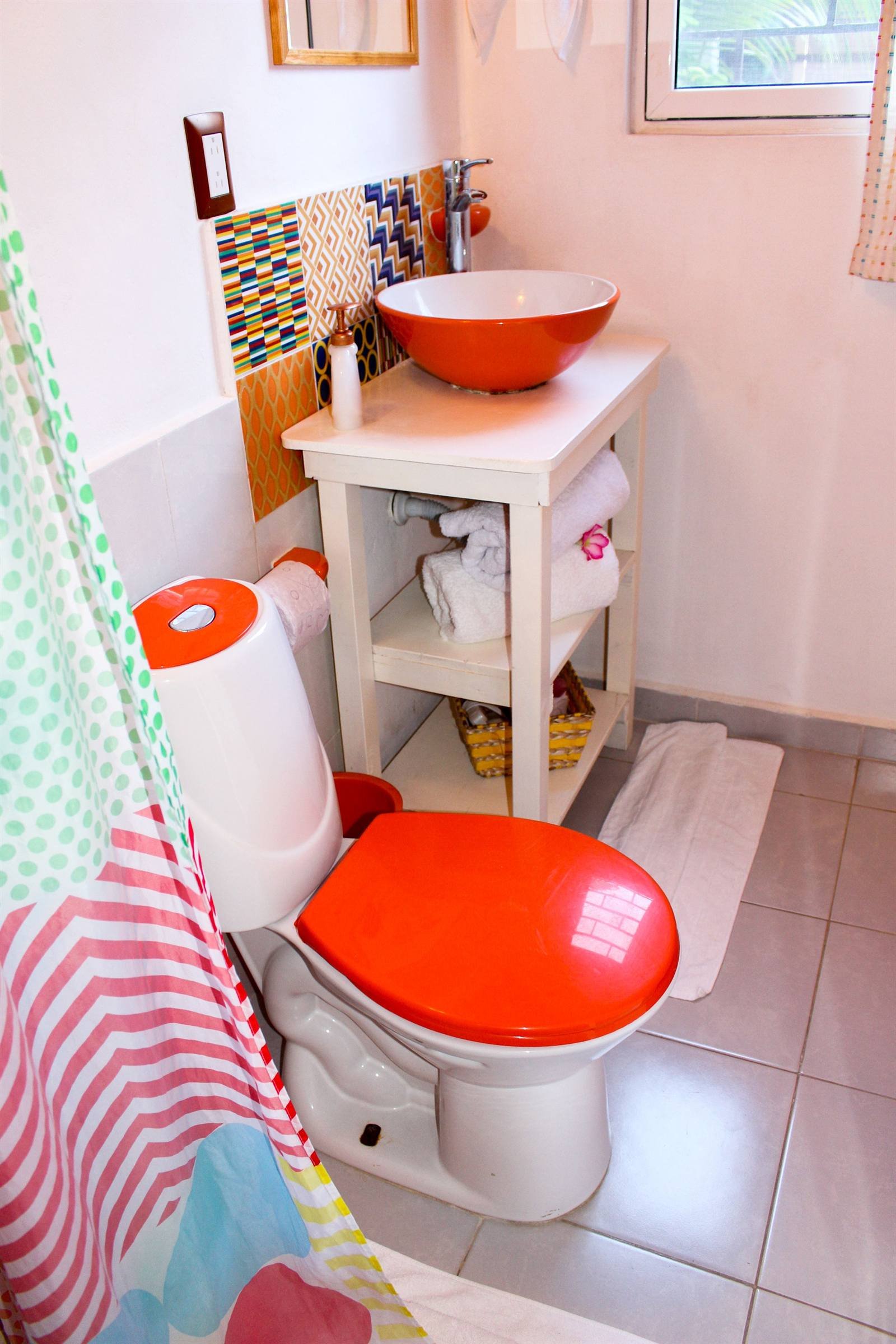 Private bathroom with an orange sink and patterned wall